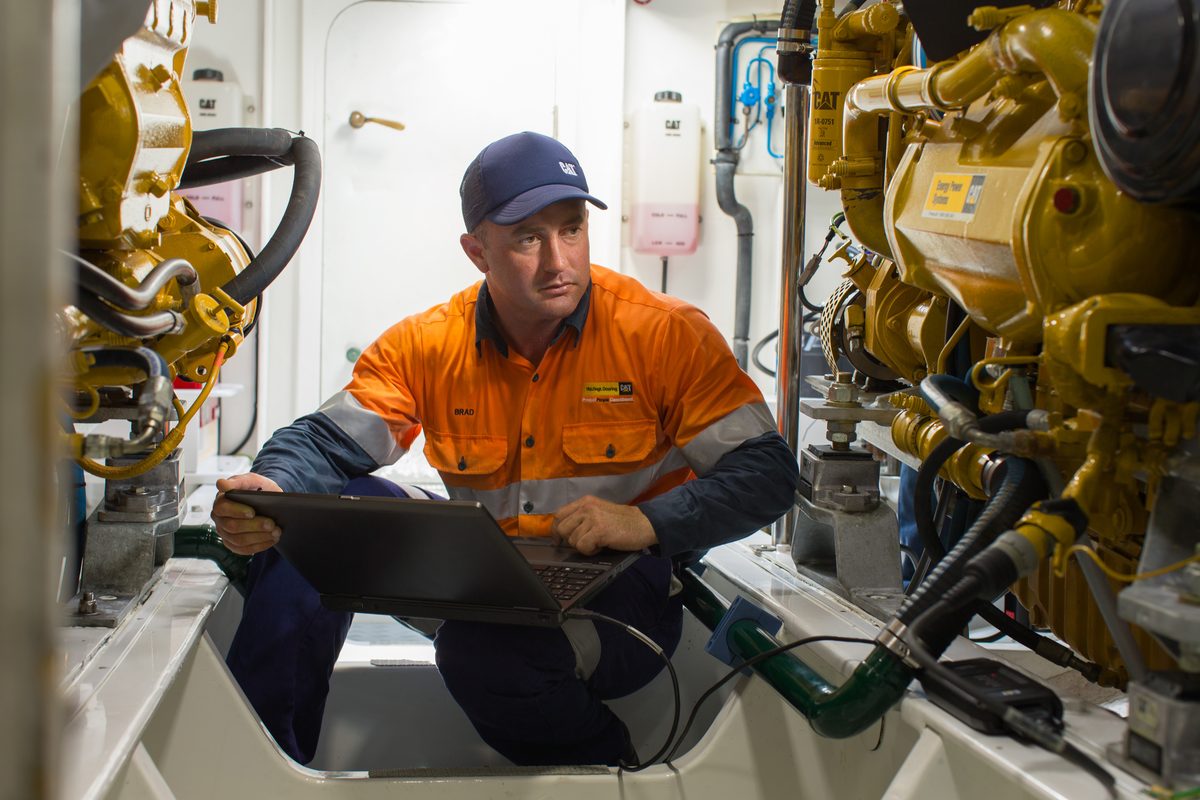 Marine technician with laptop in engine room
